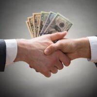 40871344 – close-up of two businesspeople shaking hands with money
